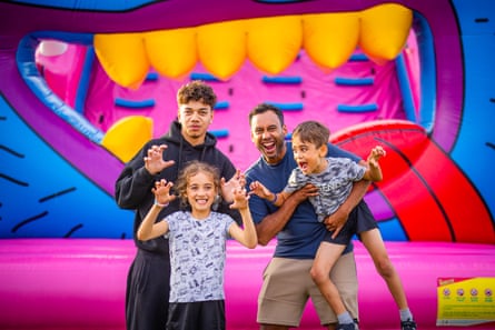 Adult, older child and two younger children do pretend to be monsters with colourful mouth of bouncy castle behind