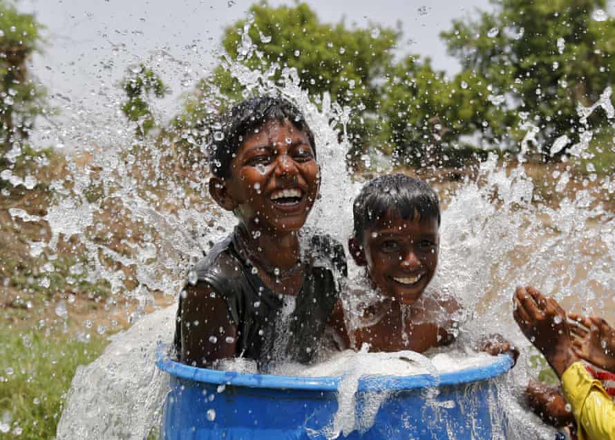 Boys sit in a plastic container filled with water on the outskirts of Ahmedabad