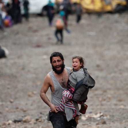A man cries while carrying his small daughter, who is also crying