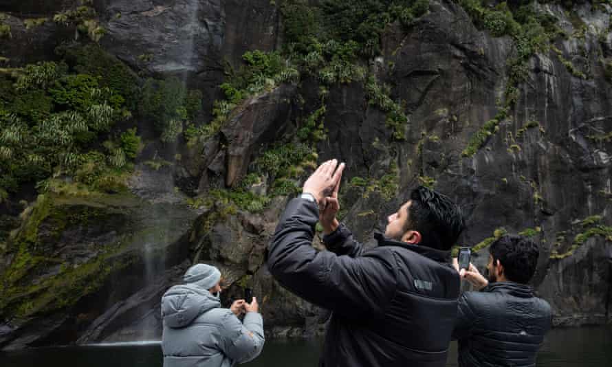 Les visiteurs prennent des photos depuis un bateau de croisière à Milford Sound.