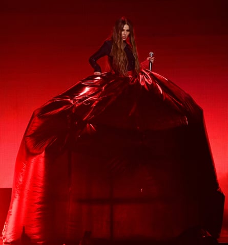 Cheryl wearing a dark, sparkly top and a 10-foot-tall red inflatable skirt against a red backdrop