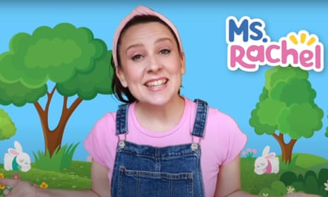 a woman in a pink T-shirt and blue overalls in front of an illustration of trees and bunnies