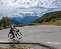Male cyclist riding uphill through bend in the French Alps
