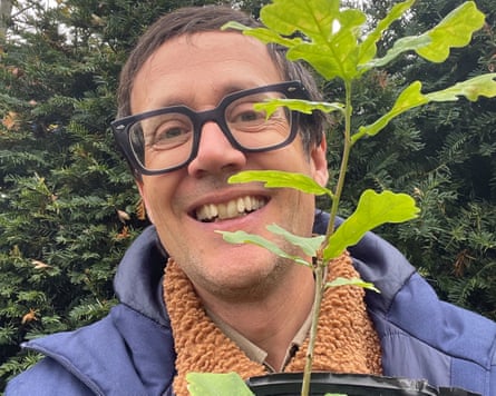 Barkham holding a young oak tree in a pot.