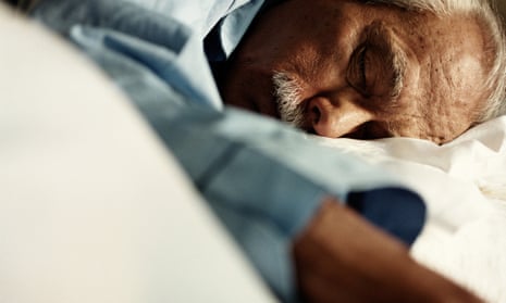 An older man asleep in bed.