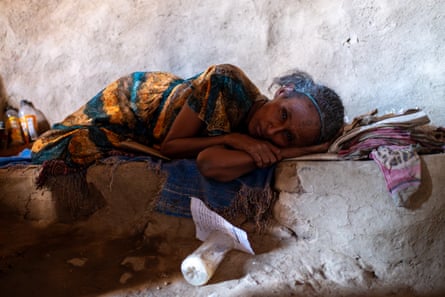 A sick woman lies on a stone bench