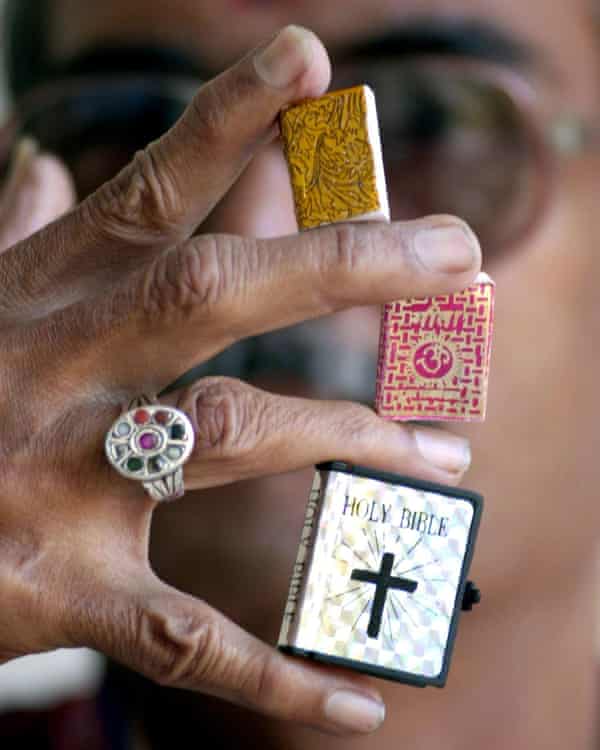 Jagadish Shukla, a magician, holds his miniature copies of a Koran, the Bhagavad Gita and the Bible in Bangalore in 2001.