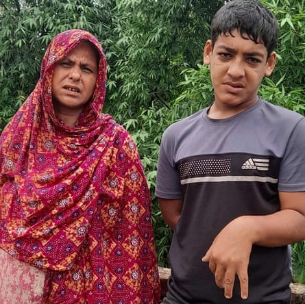 A middle-aged south Asian woman in a floral hijab beside a teenage boy