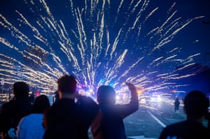 People watch as the sky is lit up with lights from clashes