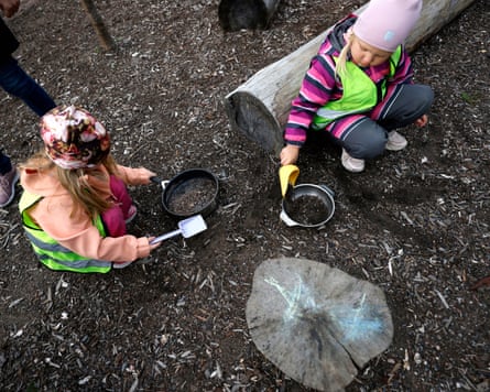 Two children play with pots in the dirt