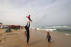 A child is tossed in the air on the beach