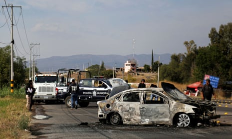 Police stand by the wreckage of a burned-out car on the outskirts on Celaya in Guanajuato. A top analyst said it was ‘business as usual’ for the cartels.