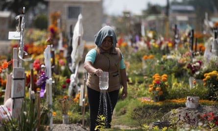 A woman waters her father’s grave at the Valle de Chalco municipal cemetery on the outskirts of Mexico City on Thursday.
