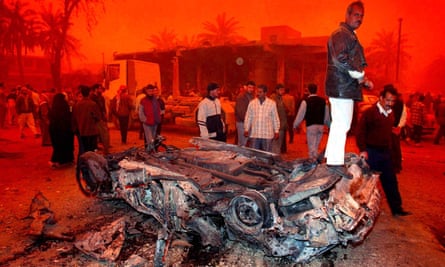 Iraqis protest in Baghdad surrounded by a red-tinted sky caused by severe dust storms and burning oil fires on 26 March 2003
