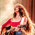 A woman with long, flowing hair plays an acoustic guitar