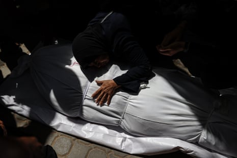 A Palestinian woman mourns over the body of a relative wrapped in a white shroud at al-Shifa hospital after an Israeli airstrike on a civilian vehicle in central Gaza City on Saturday.