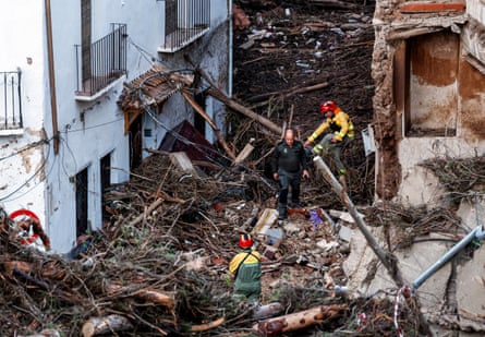 emergency workers navigate a street covered in debris following a flash flood
