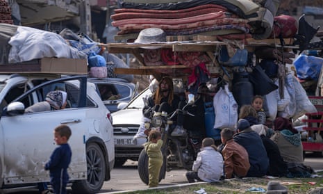 People gather with their belongings gather near a roadblock on Salah al-Din Street as Israeli forces delay reopening access to the north of the Gaza Strip.