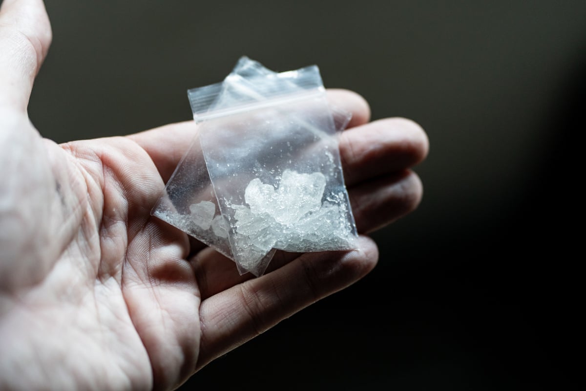 A person holds a bag of crystal methamphetamine.