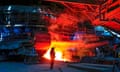 Man in protective gear stands in front of fire and machinery