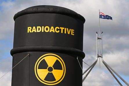 A large inflatable barrel marked ‘radioactive’ with the flag above Parliament House in the background