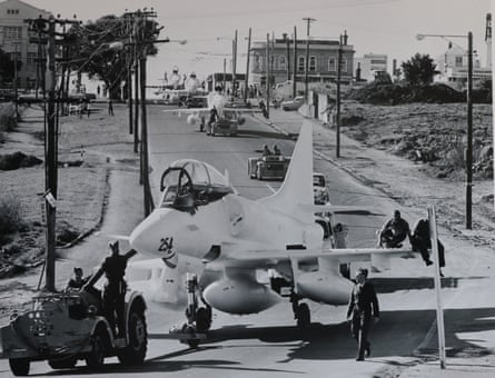 Four jet fighters being towed through suburban streets