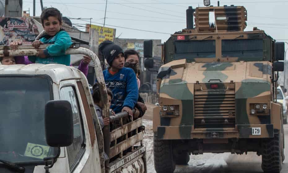 Displaced Syrians and a Turkish military armoured vehicle in Idlib, Syria. 