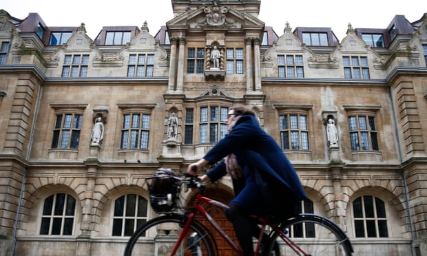 woman rides bike past Rhodes statue at Oriel College, Oxford