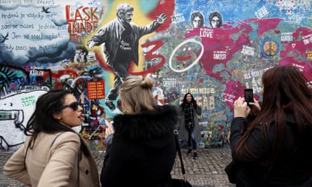 Tourists pose near a painting of Václav Havel on the Lennon wall.