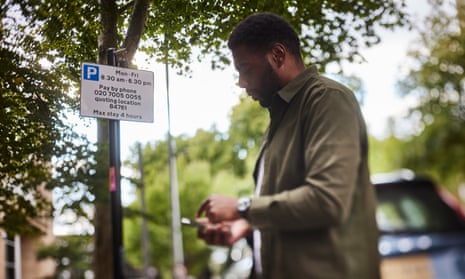 A man uses a smartphone and app to pay for street parking