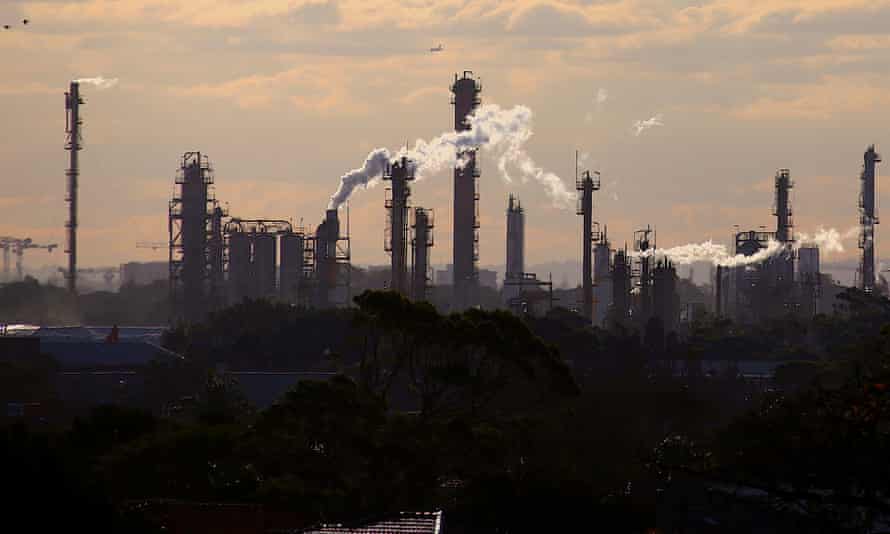 Birds and a plane are seen flying above emission from the chimneys of a chemical plant located near Port Botany in Sydney