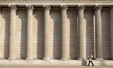 A woman in a face mask walks past the Bank of England