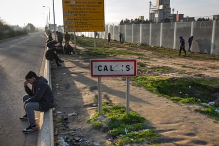 Migrants wait by the roadside in Calais