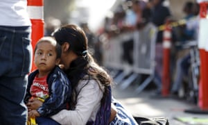 A woman sits with her sons as they wait to apply for asylum in the US along the border in Tijuana, Mexico. on July 2019.