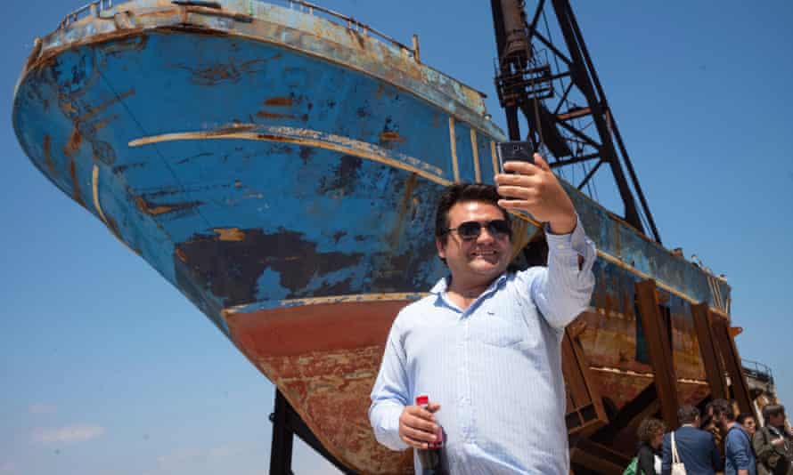 A man takes a selfie in front of Barca Nostra, exhibited at the Venice Biennale