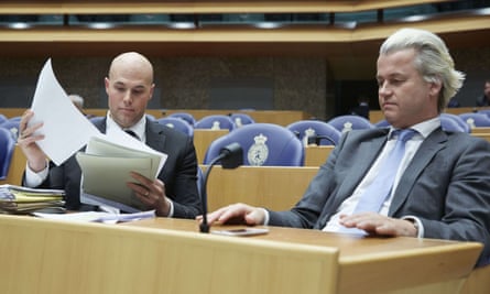 Joram van Klaveren looks through a sheaf of papers as he sits next to Geert Wilders at a desk in the Dutch parliament