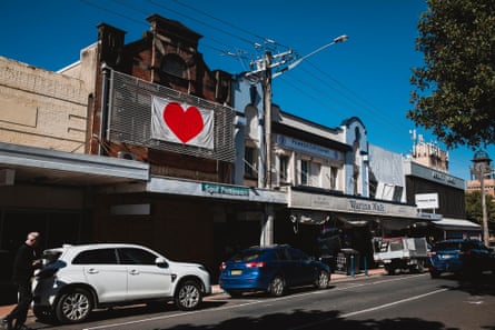 A banner displaying a red heart hangs above a shopfront on a high street in Lismore