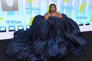 Lizzo is on the black carpet wearing a billowing and voluminous navy blue dress