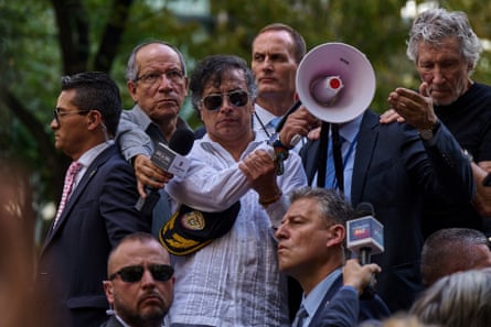 A man stands surrounded by bodyguards speaks into a megaphone