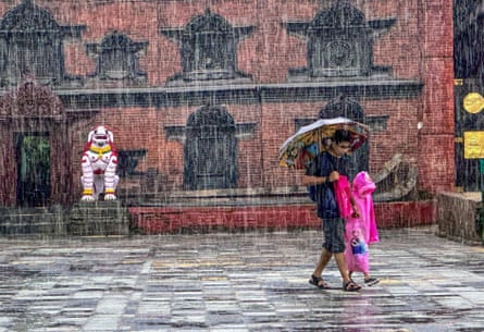 A man carrying an umbrella and a child walk through a square