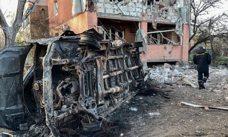 A rescuer walks near a destroyed car and an apartment building after the Russian missile attack on April 9, 2024 in Poltava, Ukraine.
