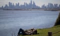 Man resting on grass with view of Melbourne CBD across water