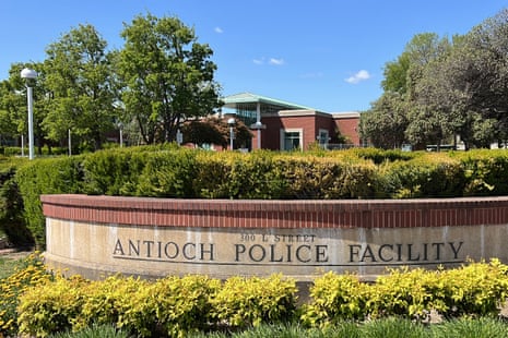 A stone and brick sign engraved with the words 'Antioch Police Facility' is surrounded by green hedges outside a brick building.