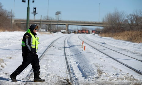 A police officer crosses the railway tracks in front of where protesters maintain a railway blockade in St-Lambert.