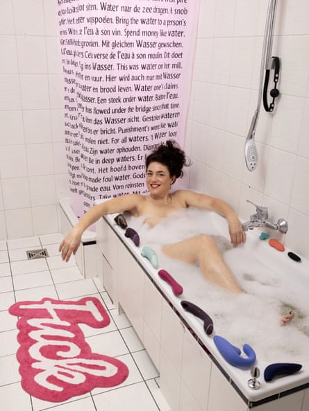 Portrait of Alexis lying in a bubble bath with her sex toys arranged around the rim of the bath