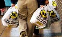 A rear view of a shopper leaving a Morrisons supermarket with carrier bags