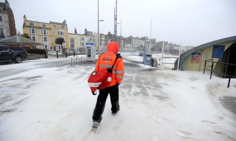 A postal worker makes deliveries along Weymouth beach in Dorset