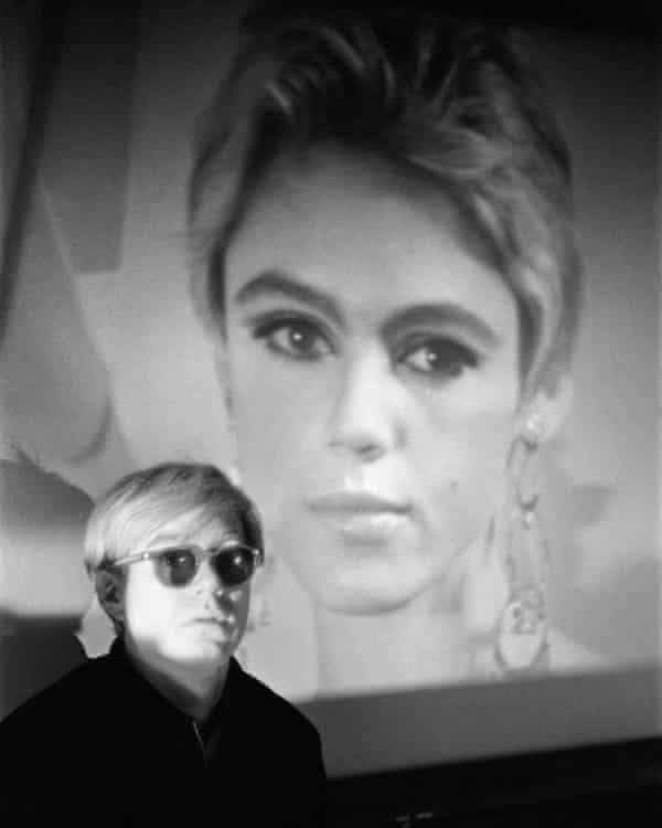 Warhol in his studio in front of one of the Beauty films featuring Edie Sedgwick, 1965.
