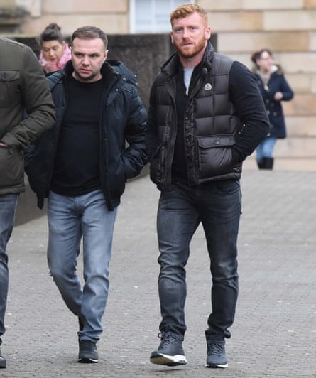 Gangsters Ross Monaghan and Eddie Lyons Jr walk along a street in jeans and puffer jackets