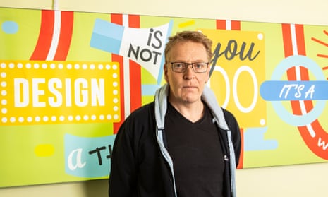 Portrait of Andrew Moss standing in front of a colourful wall sign